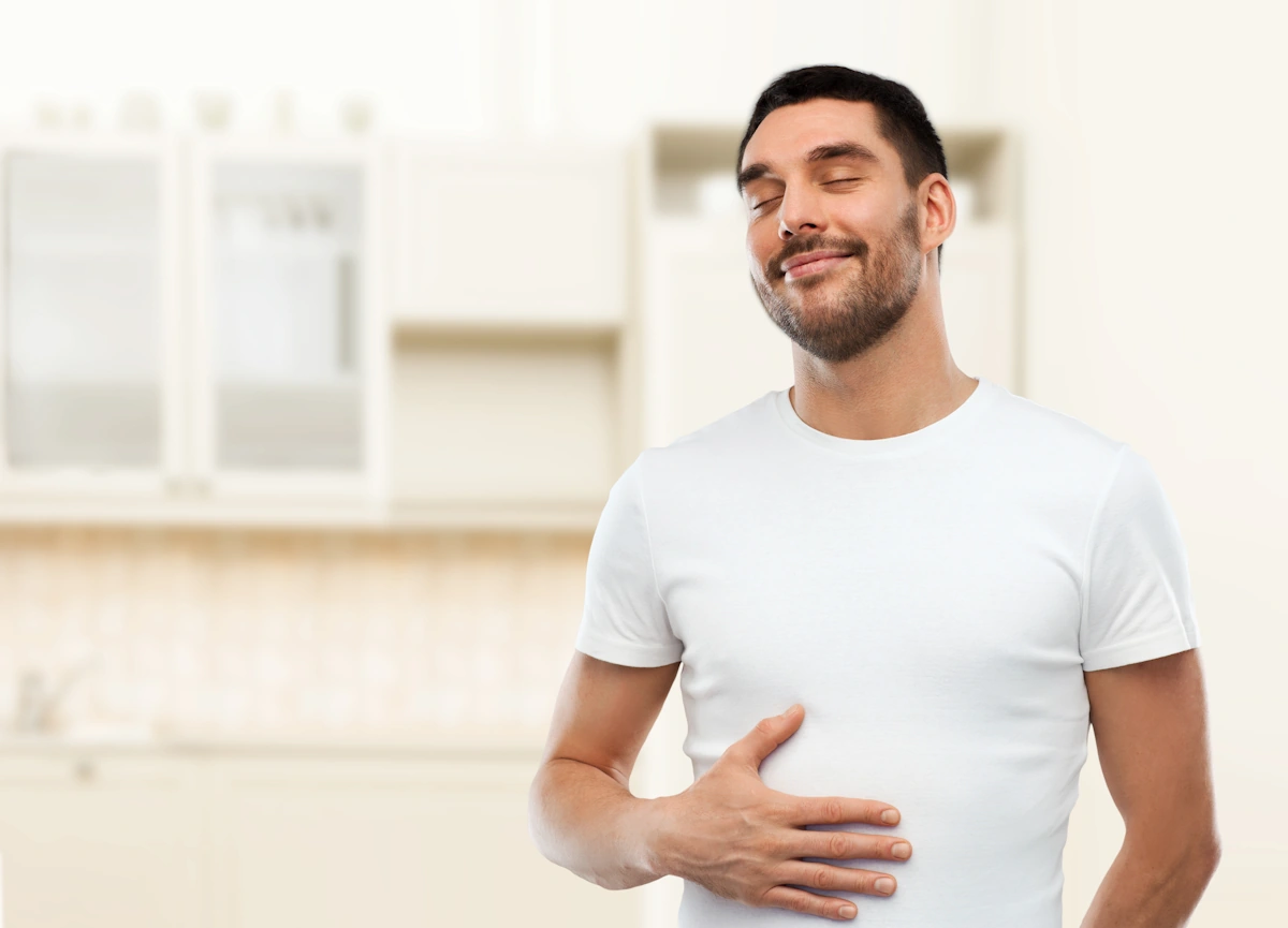 Un homme qui sourit en tenant son ventre