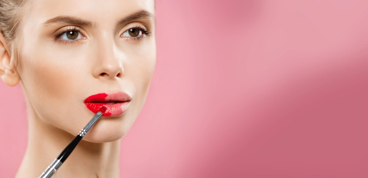 Une femme au peau claire qui applique du rouge à lèvre