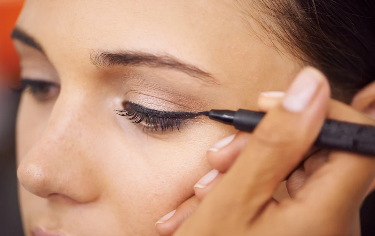 Une femme qui se fait appliquer un  eye liner 