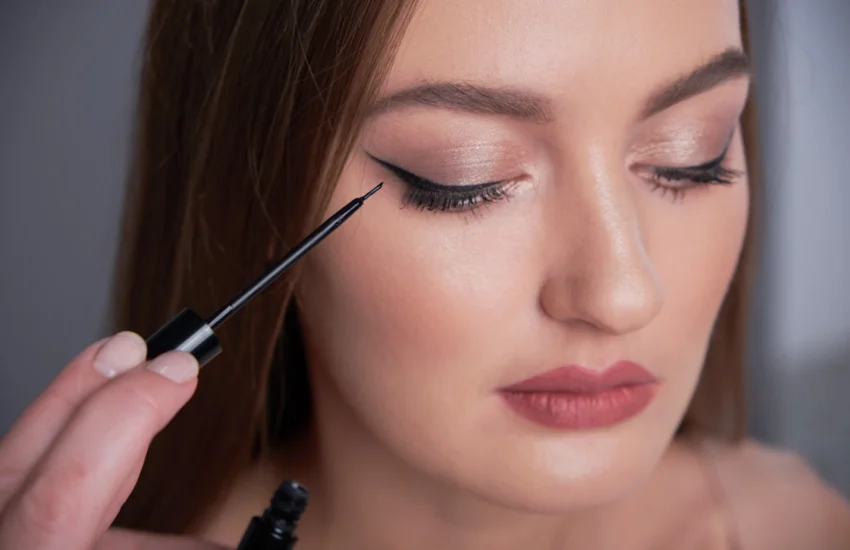 Une femme qui applique un trait eye liner yeux tombant