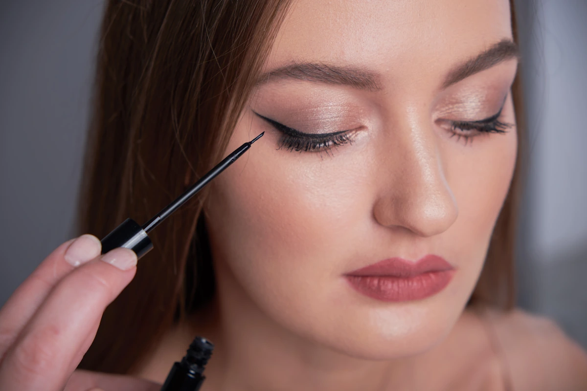 Une femme qui applique un trait eye liner yeux tombant