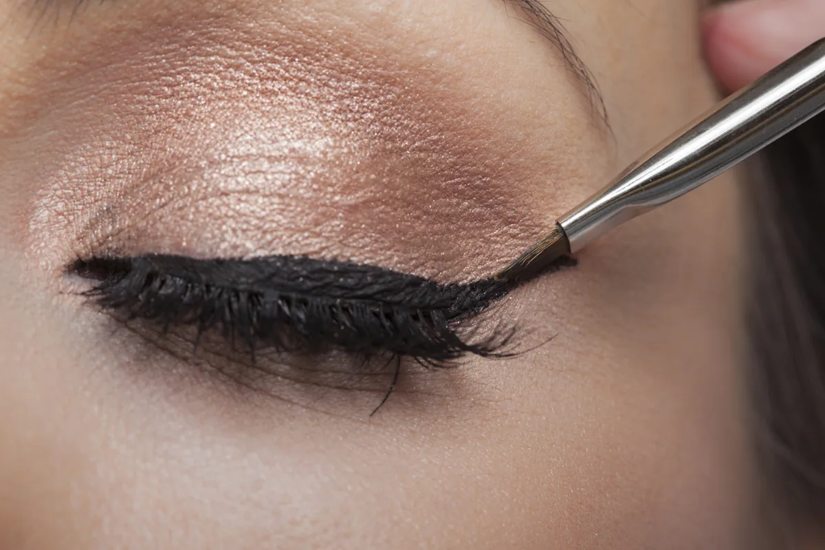Une femme qui applique un trait eye liner